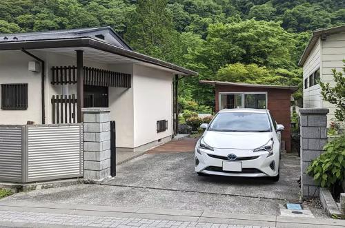 a white car parked in front of a house at Nikko Takumi Best Views in Nikko 10 Min Walk to Toshogu and Kanmangafuchi 72sqm Entire House for 8 4 Beds Beautiful Japanese Garden Free Parking Large Screen Projector Free Washer and Dryer in Nikko