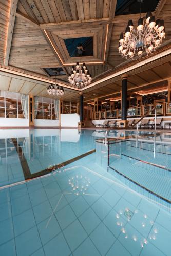 an indoor swimming pool with a wooden ceiling and chandeliers at Alpin Resort Sacher in Seefeld in Tirol