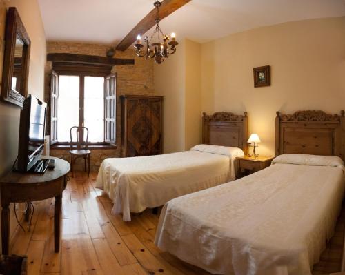 Un dormitorio con dos camas y un televisor. en Paraiso del Bierzo, en Las Herrerías