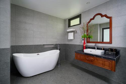 Un baño con bañera, lavabo y espejo. en Sơn Nữ Emerald Hill Hotel, en Bak Kan