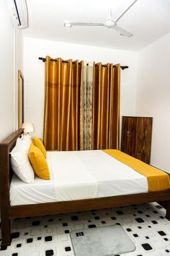 a bed with yellow and white pillows in a room at behind ocean villa in Weligama