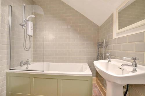 a bathroom with a sink and a tub and a toilet at Poppy Cottage in Bodham