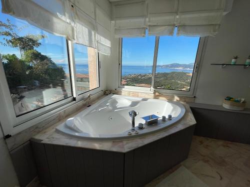 a large bath tub in a bathroom with large windows at Villa de standing 12 couchages - vue sur mer - piscine à débordement chauffée in Albitreccia