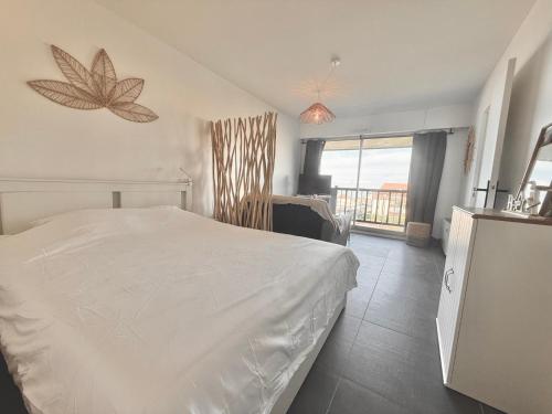 a bedroom with a white bed and a balcony at Sunset View , Studio , Parking & Wifi in Villers-sur-Mer