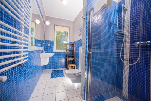 y baño azul con aseo y ducha. en Villa Mare Apartamenty, en Grzybowo