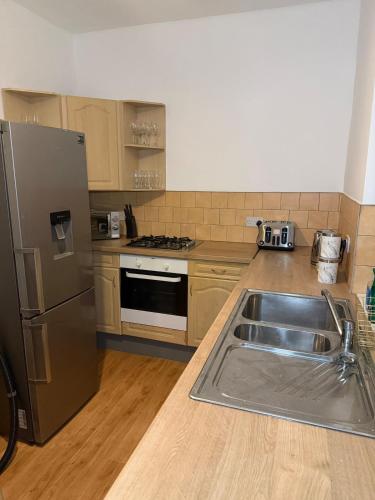 a kitchen with a sink and a stainless steel refrigerator at 2 Bedroom Wakefield City Centre House With All Ensuite Rooms in Wakefield