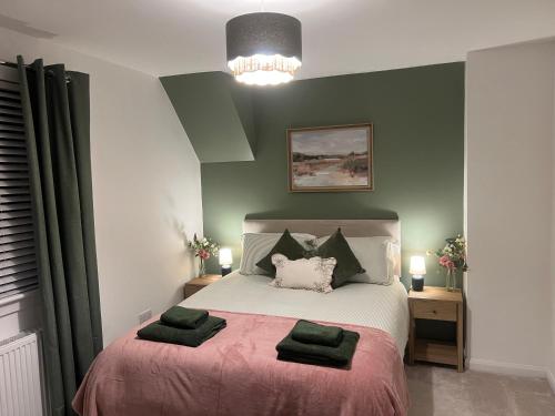 a bedroom with a large bed with green walls at 60 Springfield Road in Stornoway