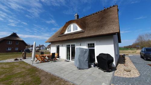 een wit huis met een bruin dak en een patio bij Ferienhaus In Mellnitz Mit Großem Garten in Poseritz