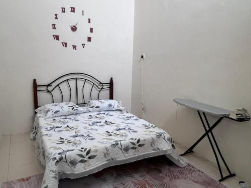 a bedroom with a bed and a clock on the wall at Lakeville Inn in Seri Iskandar