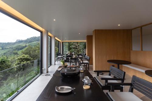 Un restaurante con mesas y sillas y grandes ventanales. en Mobu Chiang Rai, Thailand, en Ban Sam Laem