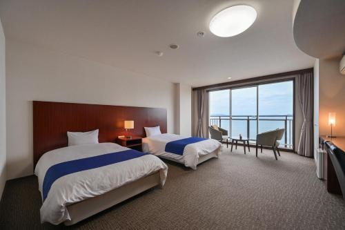 a hotel room with two beds and a large window at Yunoko Umi To Yuyake in Minamata
