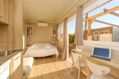 a bedroom with a bed and a desk with a laptop at Camping Vidrà in Vidrá
