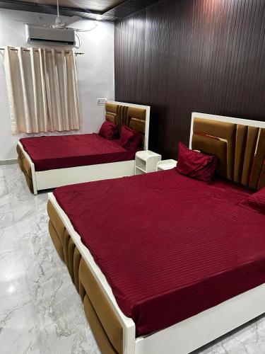 two beds with red sheets in a room at Shri omkarnath Guest house Ayodhya in Ayodhya