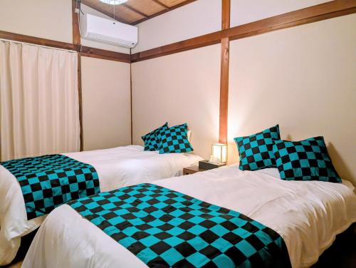 Dos camas con sábanas a cuadros en una habitación. en ann近島 無料駐車場2台 階段なし安心の平屋貸切 ファミリーやグループ旅行に最適, en Gifu