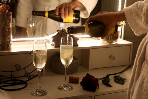 a person pouring champagne into two glasses on a counter at La Rosa di Antonio -Relax Room in Tricase