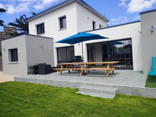 a picnic table with an umbrella in front of a house at Villa Noz Vat 4 étoiles avec SPA in Plouescat
