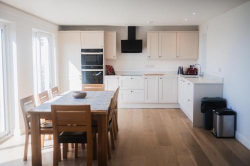 una cucina con tavolo e sedie e una cucina con mobili bianchi di Putsborough Cottage a Croyde
