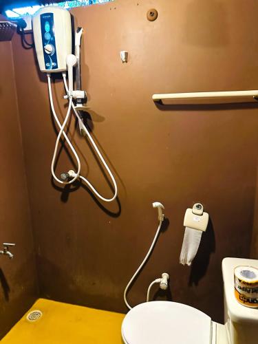 a bathroom with a toilet and a phone on the wall at Jungle Host Hostel And Tree House in Sigiriya