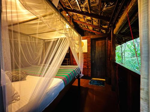 un dormitorio con una cama con mosquitera en Jungle Host Hostel And Tree House, en Sigiriya