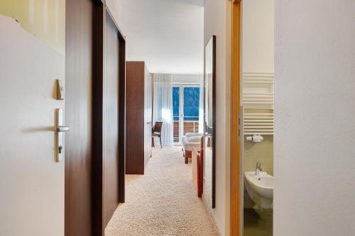 a hallway leading to a bathroom with a sink and a toilet at Kreativ Hotel Landhaus Schweigl in Ultimo
