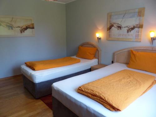 2 Betten in einem Zimmer mit orangefarbener Bettwäsche in der Unterkunft Haus der Gastlichkeit in Ratingen