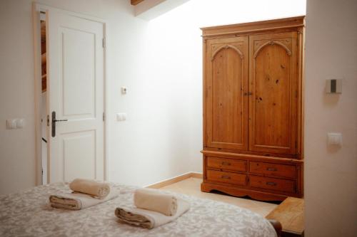 a bedroom with a wooden cabinet and two towels on a bed at Casa Roma in Raposeira