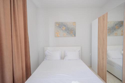 a small bedroom with a bed with white sheets at Luxury Apartment with Parking in Tirana