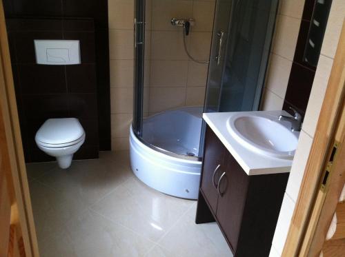 a bathroom with a tub and a toilet and a sink at Ośrodek Wczasowy Łowiczanka in Wisełka