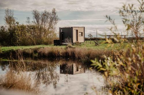 a small building sitting next to a body of water at Homnest - Loge insolite au coeur d'un ranch - Balade à cheval in Espinasse-Vozelle