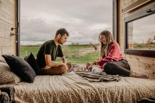 a man and a woman sitting on a bed at Homnest - Loge insolite au coeur d'un ranch - Balade à cheval in Espinasse-Vozelle