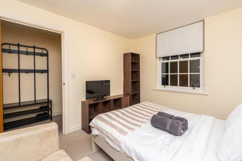 a bedroom with a bed and a flat screen tv at Amanah Properties - Elegant Home in Shepherds Bush, steps from Westfield, Sleeps 8 in London