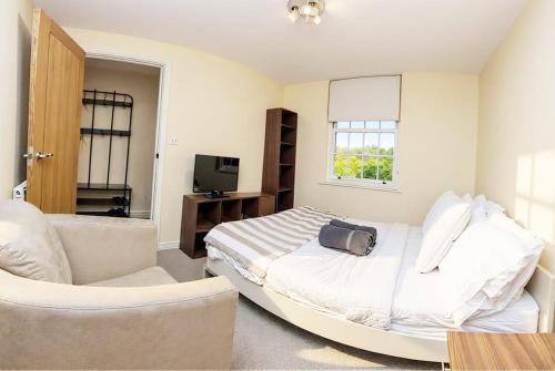 a bedroom with a bed and a couch and a television at Amanah Properties - Elegant Home in Shepherds Bush, steps from Westfield, Sleeps 8 in London
