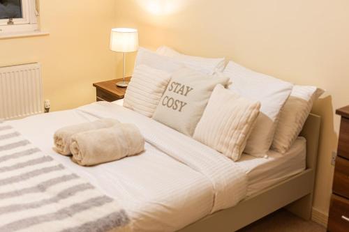 a white bed with white pillows and a sign on it at Amanah Properties - Elegant Home in Shepherds Bush, steps from Westfield, Sleeps 8 in London
