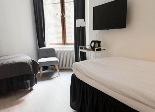 ヨーテボリにあるHotel Lemonadeのベッドと椅子とテレビがあるホテルの部屋