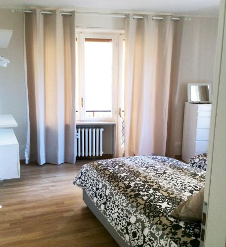 a bedroom with a bed and a window with curtains at Lilly Rose Apartment in Alba