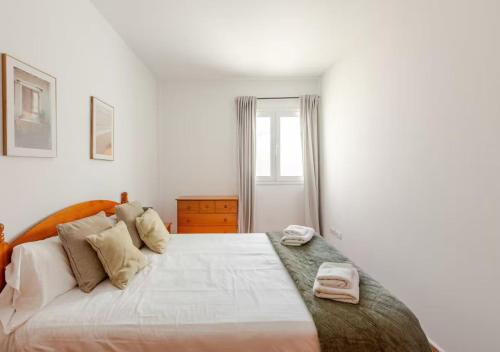 a white bedroom with a large bed with two towels on it at Playa Azul Amplio y luminoso con vistas al mar in Pozo Izquierdo