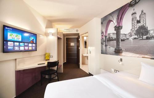 a hotel room with a bed and a flat screen tv at B&B HOTEL Krakow Centrum in Kraków