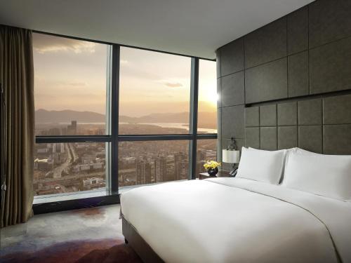 a bedroom with a large white bed and large windows at Sofitel Kunming in Kunming