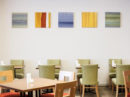 ein Raum mit Tischen und Stühlen und Gemälden an der Wand in der Unterkunft Ibis Styles Sapporo in Sapporo