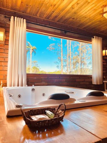 a bath tub in a room with a large window at Maria Rita dos Canyons in Praia Grande