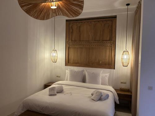 a bedroom with a white bed with two towels on it at Riad A l'Ombre du Palais in Oulad Akkou
