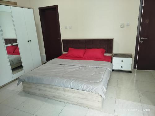 a bedroom with a large bed with red pillows at The Welcoming Wing in Ajman 