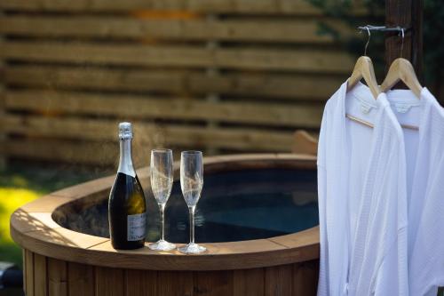 a bottle of wine and two champagne glasses on a hot tub at Cwtch Ffynnone Luxury Shepherds Hut in Newchapel