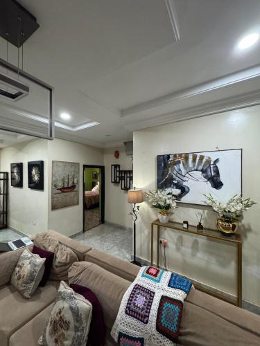 a living room with a couch and paintings on the wall at Exotic Modern 2BR Apartment in Independence Layout in Enugu