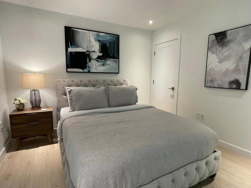 a white bedroom with a large bed and a night stand at Bright warm & spacious 1 BR in North End Halifax in Halifax