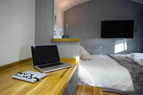 a laptop computer sitting on a desk next to a bed at Cwtch Ffynnone Luxury Shepherds Hut in Newchapel