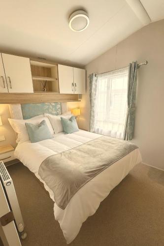 a large bed in a room with a window at Whispering Dunes - Silver Sands Holiday Park in Lossiemouth