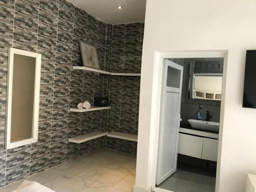 uma casa de banho com um lavatório e uma parede de tijolos em chamis apartment em Bijilo