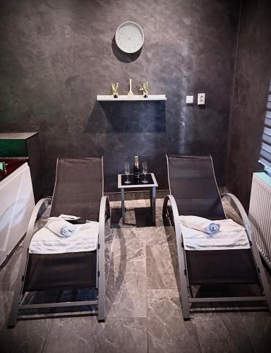 Habitación con 2 sillas y mesa con reloj en la pared en wellnesshonezovice, en Honezovice