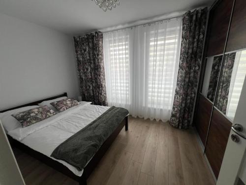 a bedroom with a bed and a large window at Apartament Zacisze in Kalisz